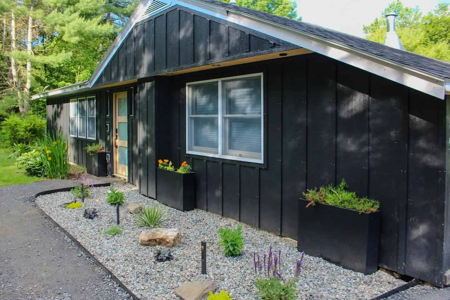 Black board-and-batten house with a gravel garden