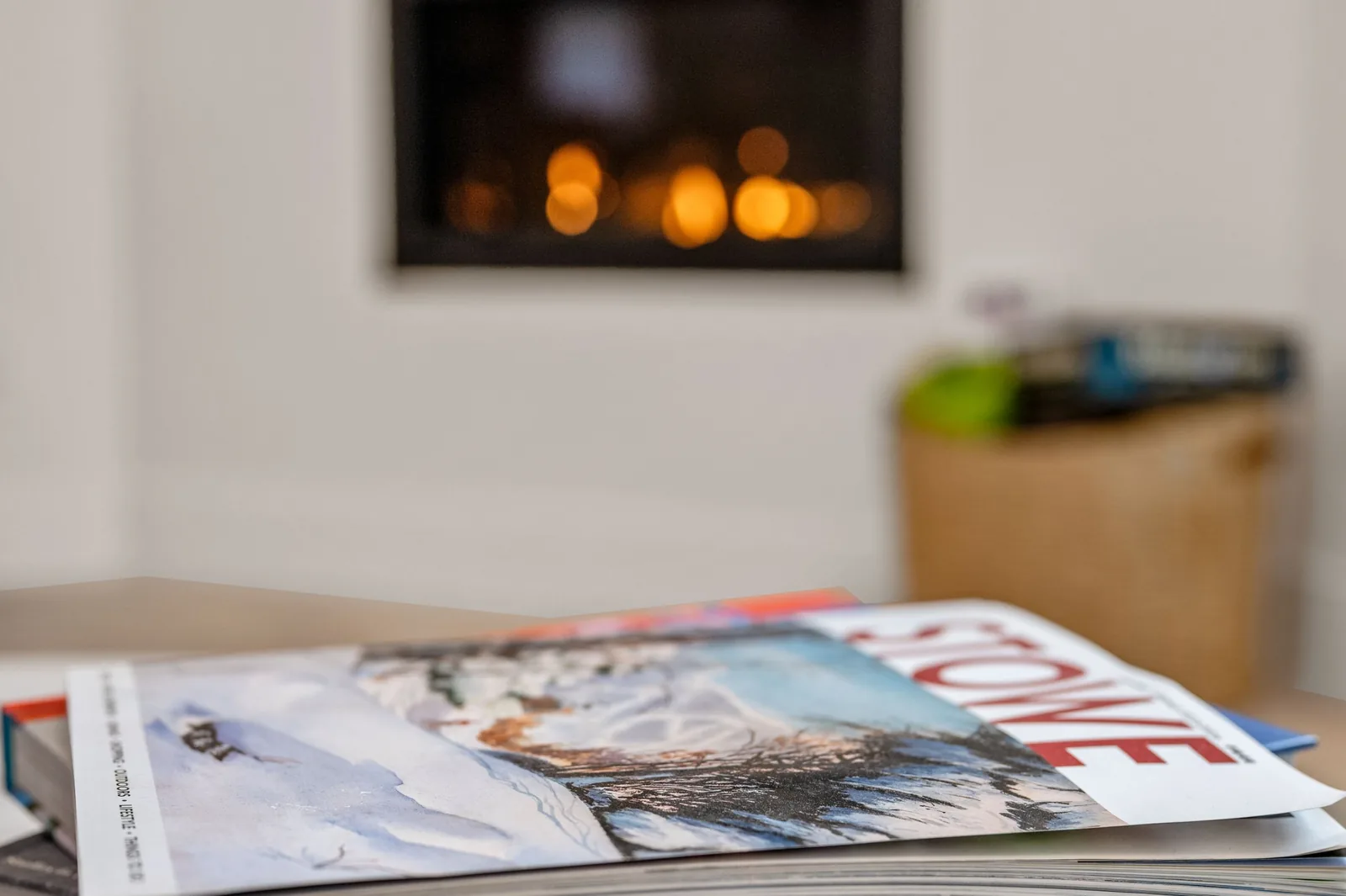 Stowe magazine and books on a coffee table in front of the glowing gas fireplace