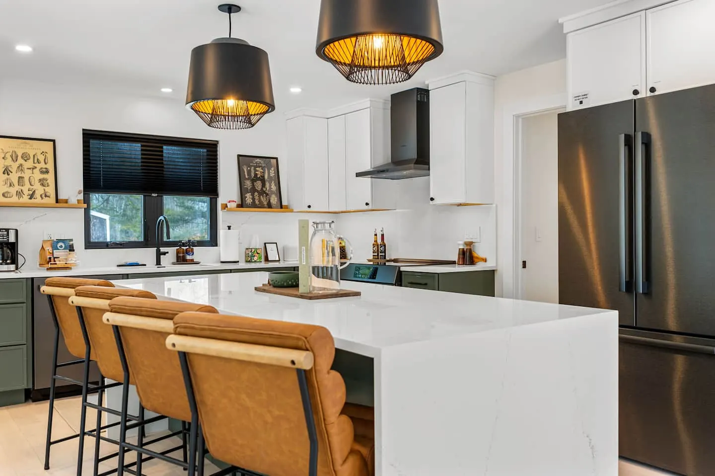 Kitchen with a white island, four leather stools and black pendant lights