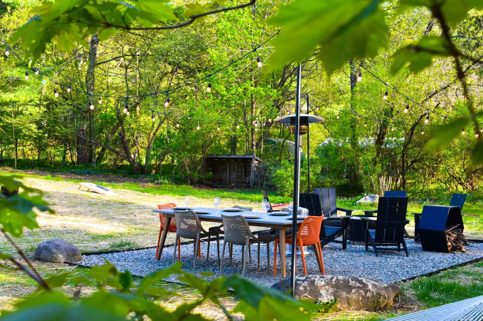 Outdoor dining table for six under string lights with a propane stand heater