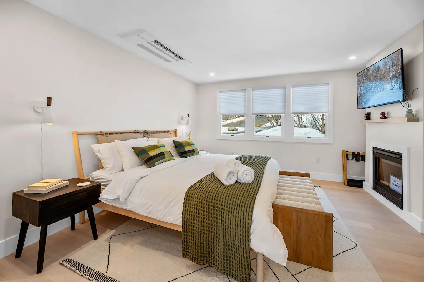 Primary suite with a king bed, wall-mounted fireplace and TV, and large windows
