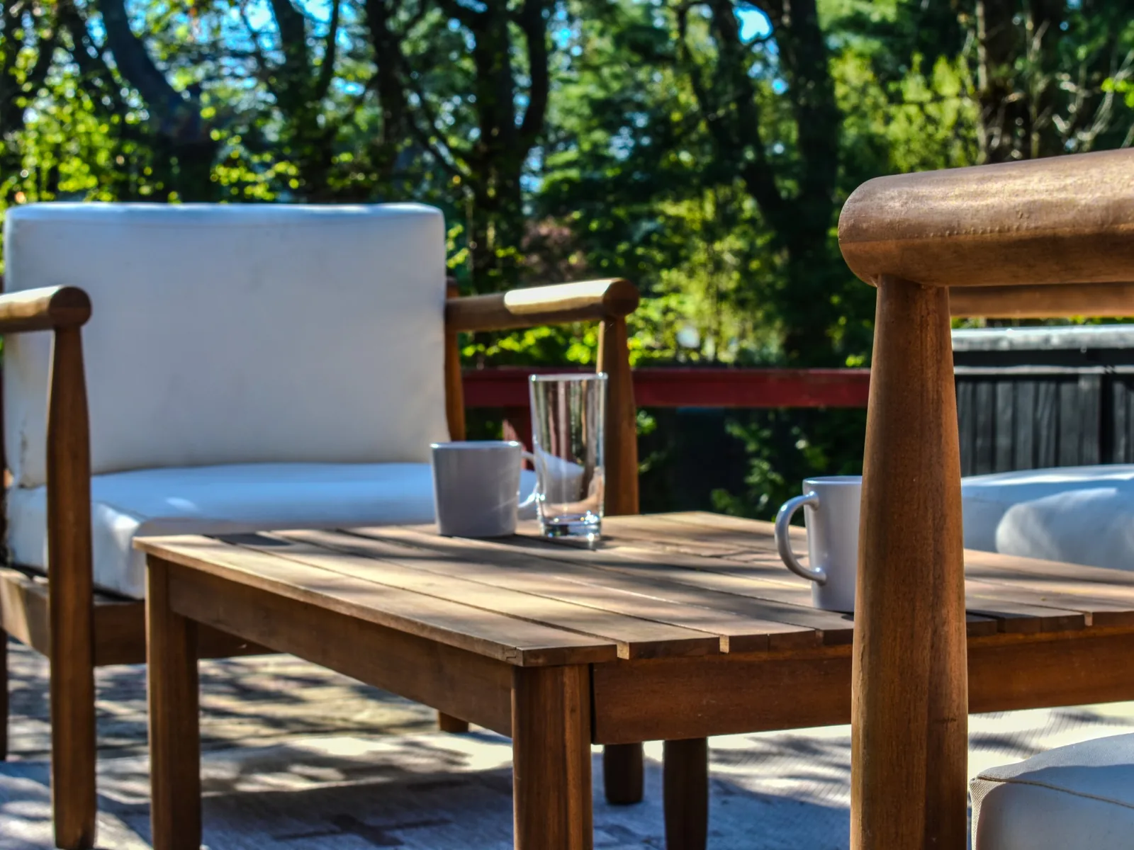 Coffee mugs on a wooden table with lounge chairs on the deck