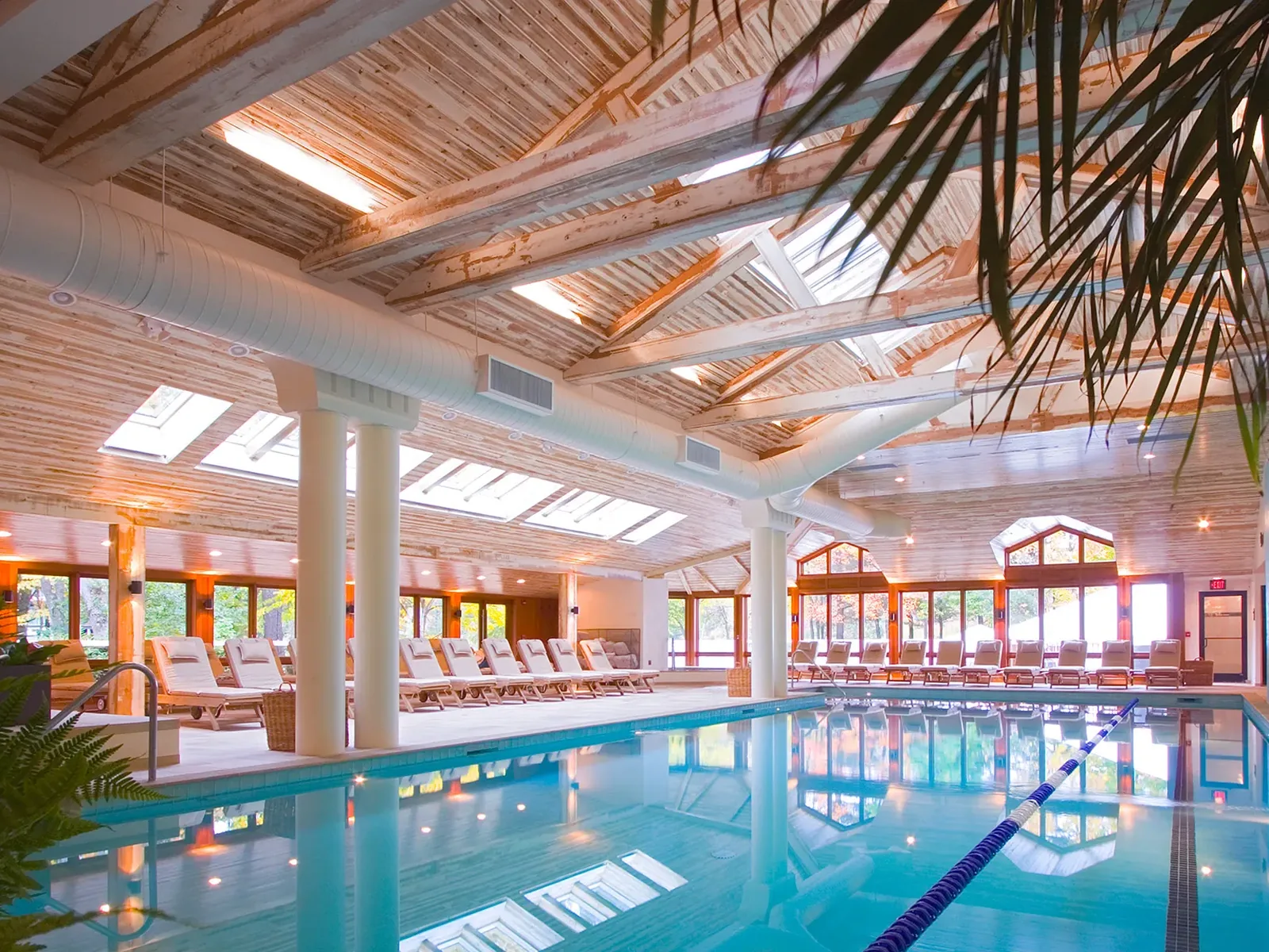 Indoor spa pool with lounge chairs under a skylit wood ceiling, an off-property spa day idea