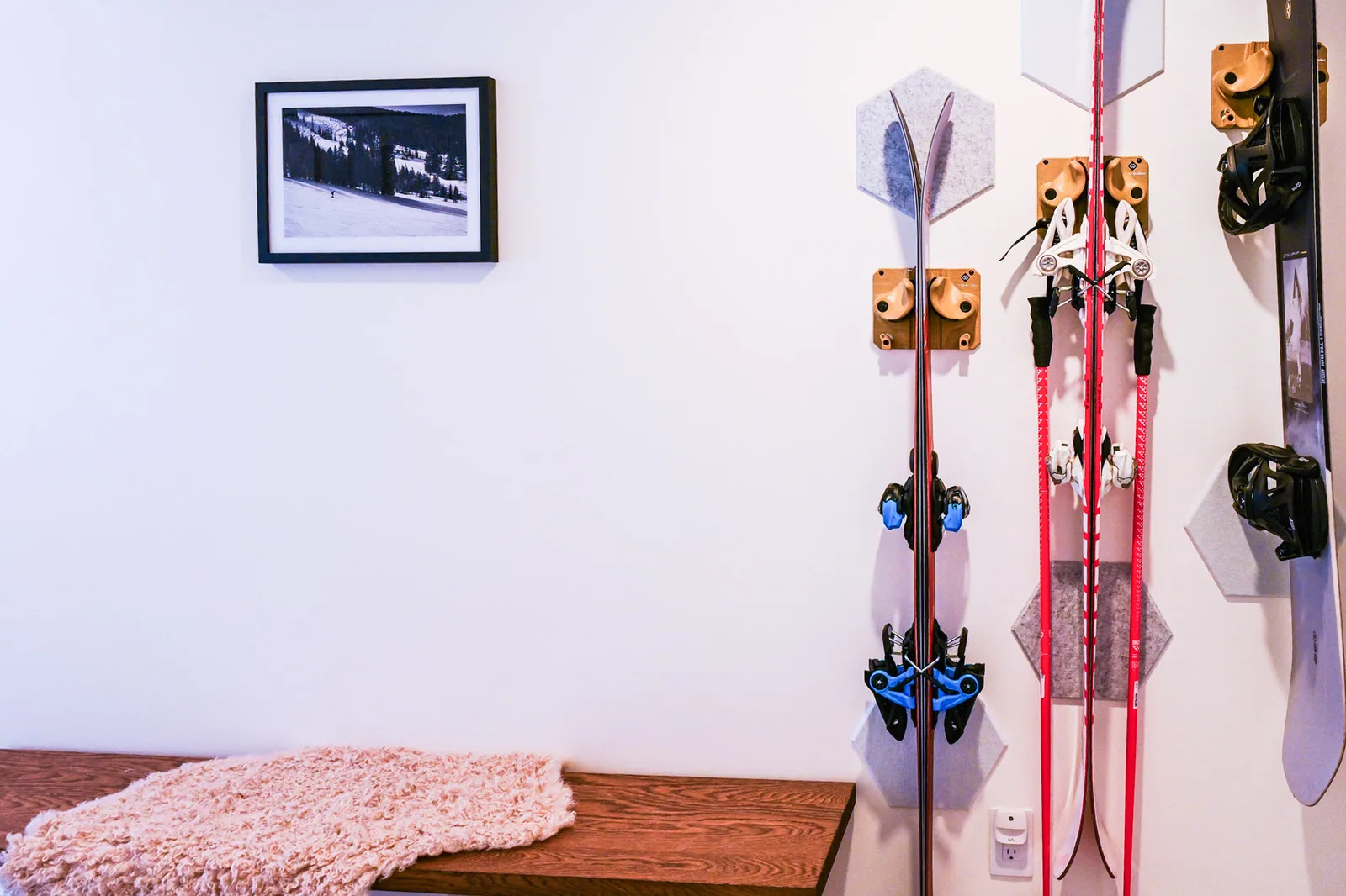 Wall-mounted ski and snowboard racks beside the entry bench