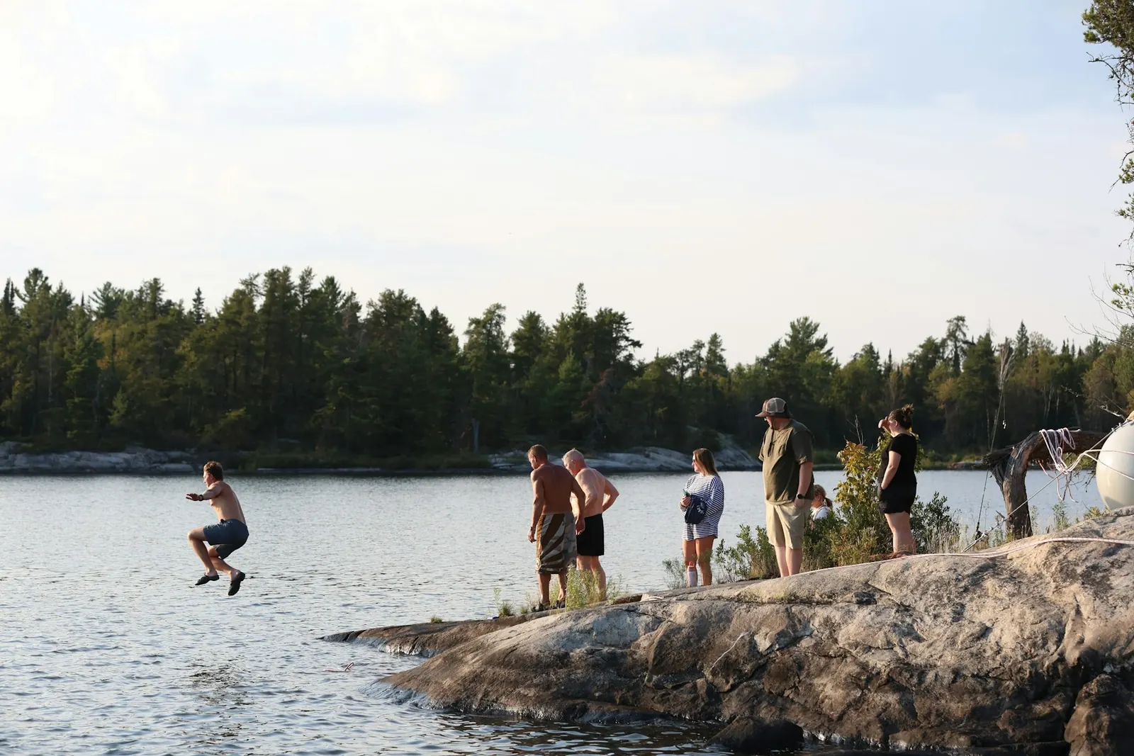 Friends jumping into a lake from the rocks